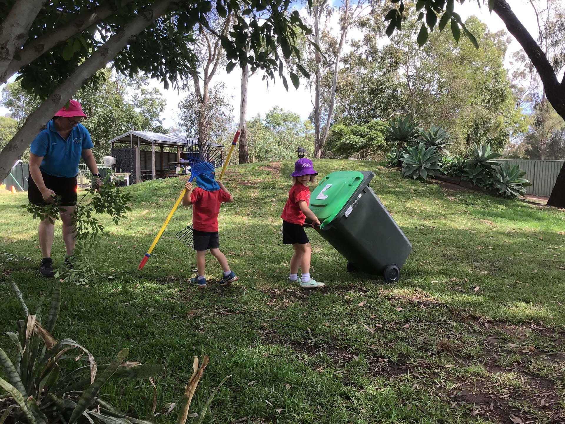 Children helping to clean up the garden as part of the commitment to children learning how to respect and care for our environment.